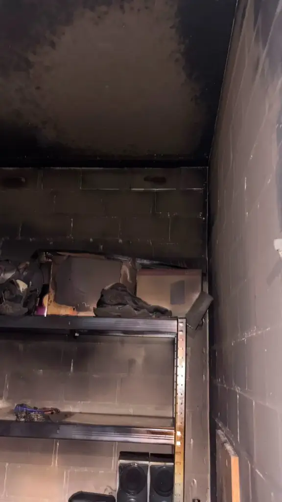 Verrußtes Regal, Mauerwerk und Decke in einem Kellerabteil nach dem Brand