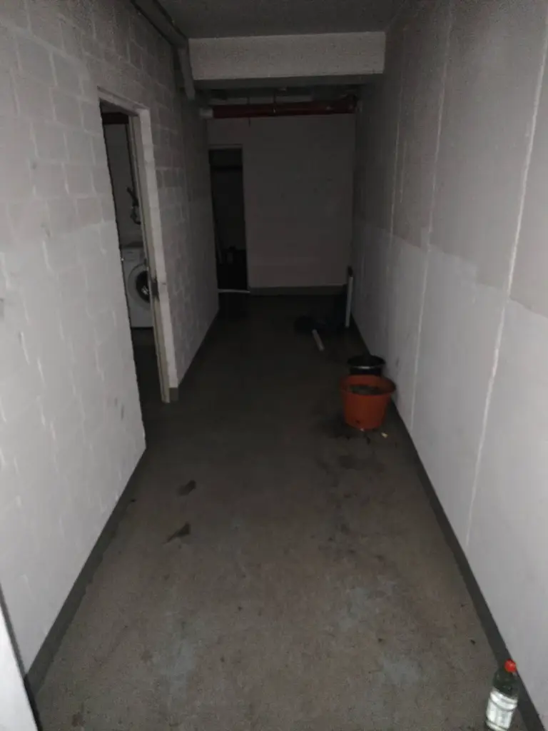 Kellerflur in Warendorf vor der Sanierung: rußgeschwärzte Wände und verschmutzter Boden nach dem Brand